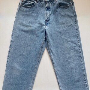 May include: Light blue denim jeans with a classic five-pocket design. The jeans have a straight leg cut and a button and zipper closure. The denim has a faded appearance, with visible stitching details.