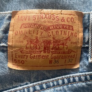May include: Close-up of a light blue denim jeans with a brown leather label. The label reads "LEVI STRAUSS & CO. ORIGINAL RIVETED QUALITY CLOTHING" with "550" and measurements W36 L32.
