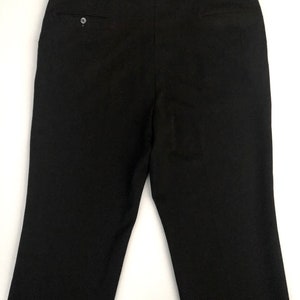 May include: Black dress pants with a buttoned back pocket and a buttoned closure. The pants are made of a smooth, solid fabric and have a classic, tailored design. The pants are suitable for formal or business attire.