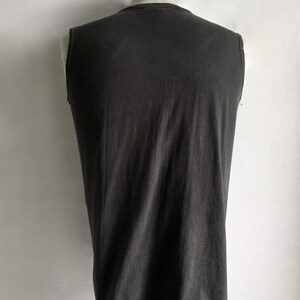 Puede incluir: Una camiseta sin mangas de color carb&oacute;n exhibida en un maniqu&iacute;. La camiseta tiene un dise&ntilde;o simple y cl&aacute;sico con una apariencia ligeramente descolorida. La tela parece suave y desgastada, lo que sugiere comodidad y uso informal.