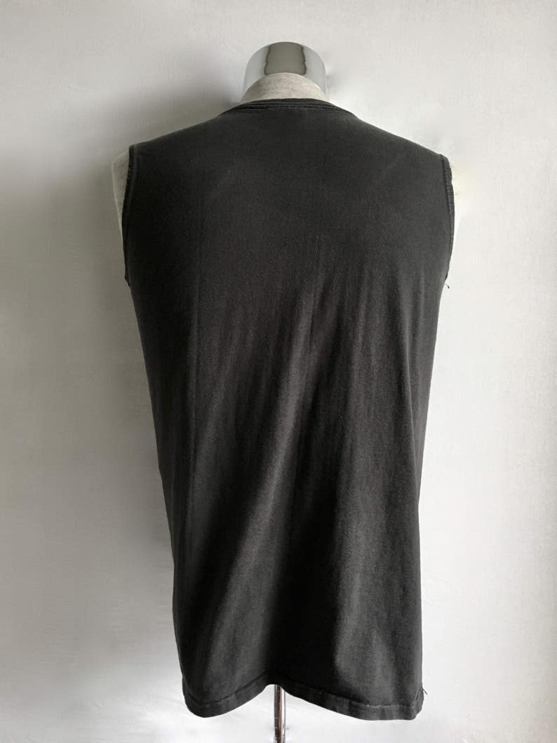 Puede incluir: Una camiseta sin mangas de color carb&oacute;n exhibida en un maniqu&iacute;. La camiseta tiene un dise&ntilde;o simple y cl&aacute;sico con una apariencia ligeramente descolorida. La tela parece suave y desgastada, lo que sugiere comodidad y uso informal.