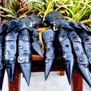 May include: A pair of black metal gauntlets with claw-like fingers. The gauntlets are decorated with rivets and have a textured surface.