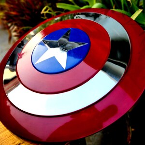 May include: A red, white and blue Captain America shield with a silver metallic rim. The shield has a large, five-pointed star in the centre.
