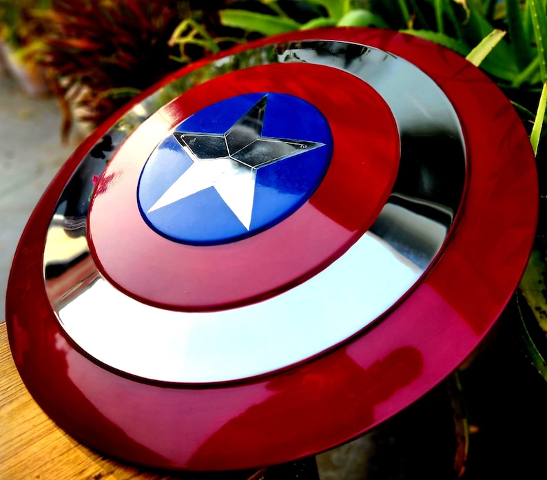 May include: A red, white and blue Captain America shield with a silver metallic rim. The shield has a large, five-pointed star in the centre.