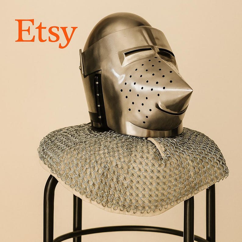 May include: A polished metal knight's helmet with a pointed visor and numerous small ventilation holes. The helmet rests on a chainmail coif, displayed on a black metal stand. The word "Etsy" is in orange text in the upper left corner.