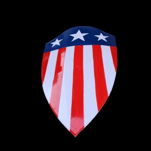 Puede incluir: Un escudo rojo, blanco y azul con cinco estrellas blancas. El escudo tiene la forma de un escudo tradicional con la parte inferior puntiaguda.