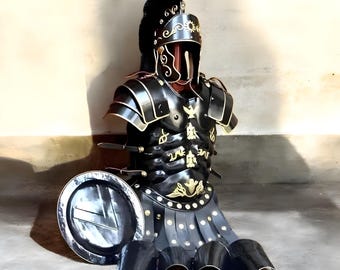 May include: A black and gold Roman armor set, including a helmet, breastplate, and skirt, with a matching shield. The armor features intricate gold detailing and is designed to resemble historical Roman military attire. The set is displayed on a mannequin.