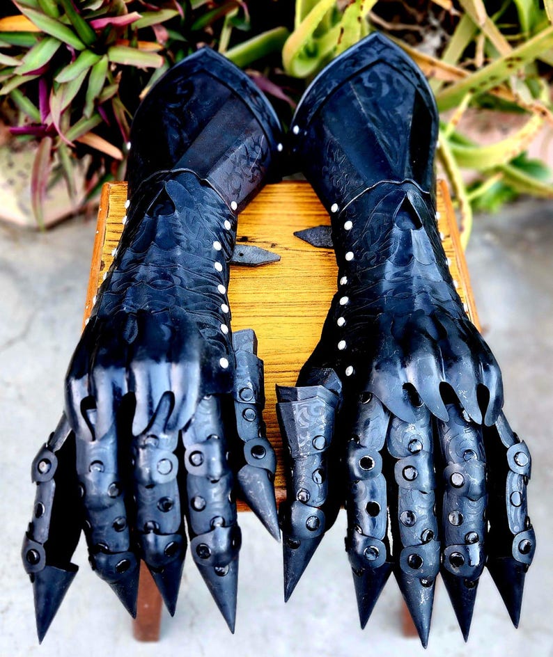 May include: A pair of black leather gauntlets with metal accents and spikes. The gauntlets are decorated with a floral pattern and have a textured surface.
