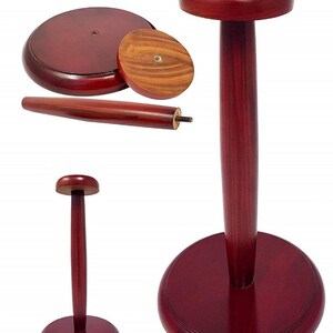 May include: A wooden hat stand with a round base and a tall, slender post. The stand is made of dark red wood and has a smooth finish.