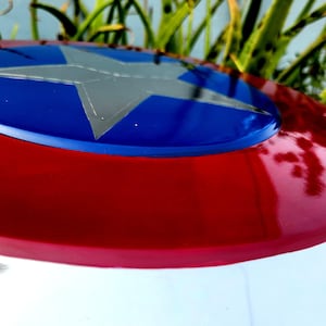 May include: A red, white and blue Captain America shield with a silver star in the centre.