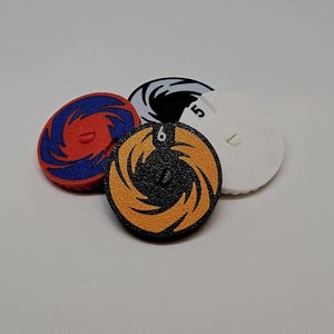 May include: Four circular game tokens with a spiral design in various colours. One is red and blue, another is orange and black with the number 6, a third is black and white, and the last is white with the number 5.