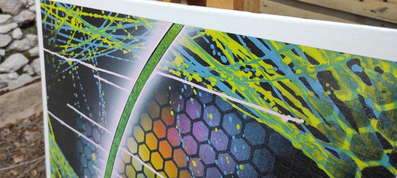 Op de afbeelding: Abstract schilderij op canvas met een zwarte achtergrond, groene, blauwe en gele verfspatten en een regenboogkleurig honingraatpatroon.