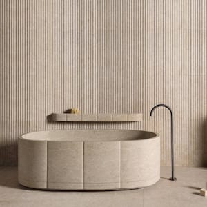 May include: A modern bathroom featuring a beige oval bathtub with a matching wall and shelf. A black faucet and small bottles are on the floor. The wall has a vertical striped pattern.