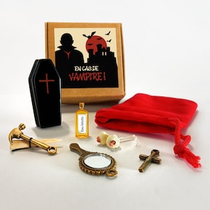 May include: A collection of miniature vampire-fighting tools, including a black coffin with a cross, a hammer, a mirror, a cross, and a bottle labeled "Eau bénite". A red drawstring bag and a box with a vampire silhouette and text are also included.