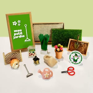 Könnte beinhalten: Eine Sammlung von Miniaturartikeln zum Thema Garten, darunter ein Schild mit der Aufschrift "mon petit jardin", grüne Handschuhe, eine Gießkanne und ein kleiner Blumentopf. Weitere Artikel sind eine Harke, eine Schaufel und eine Schere.