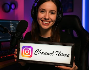 May include: A smiling person wearing headphones holds a framed sign with the Instagram logo and the words "Channel Name" in black script. A microphone and computer are visible in the background, suggesting a streaming or podcasting setup.
