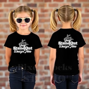 Pode incluir: Mockup de camiseta preta de manga curta para crianças com o texto "Your StandOut Design Here" na frente e atrás. A camiseta está sendo modelada por uma criança vestindo jeans preto e óculos de sol.