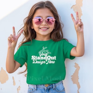 May include: A young person wearing a green t-shirt with the text "Your StandOut Design Here" in white. They are wearing pink sunglasses and smiling.