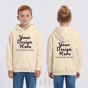 以下が含まれることがあります： 前面と背面に「Your Design Here」の文字が入ったクリーム色のパーカー。 パーカーにはフロントポケットとフードが付いています。 モデルはブルージーンズを着用しています。 テキスト「Pixel Mocks Studio」はメインテキストの下にあります。
