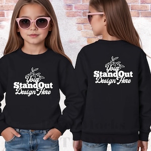 以下が含まれることがあります： 白文字で「Your StandOut Design Here」と書かれた黒いスウェットシャツ。ピンクのサングラスとブルージーンズを着用した人が着ています。デザインはスウェットシャツの背面にもあります。