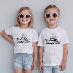 May include: Two children wearing white t-shirts with the text "Your StandOut Design Here" and a small leaf design. The children are wearing sunglasses and smiling.