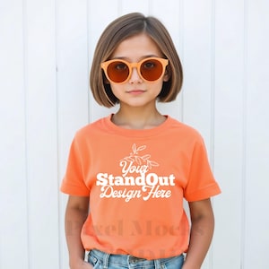 May include: A young person wearing a bright orange short-sleeved t-shirt with the text "Your StandOut Design Here" in white. The person is wearing orange-tinted sunglasses and has short brown hair.