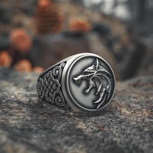 May include: A silver ring featuring a wolf head design. The ring has a detailed, ornate band.