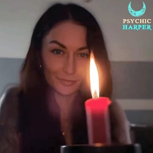 Op de afbeelding: Een vrouw met lang donker haar kijkt naar de camera terwijl ze een brandende rode kaars voor haar gezicht houdt. De tekst "PSYCHIC HARPER" is zichtbaar in de rechterbovenhoek van de afbeelding.