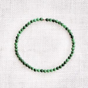 Puede incluir: Un brazalete de cuentas de piedras preciosas verdes con un cierre plateado.