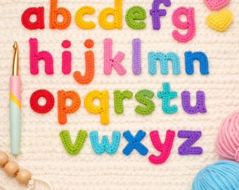 May include: A set of lowercase alphabet letters crocheted in various colours including red, orange, yellow, green, blue, purple, and pink. Two small crocheted hearts, a metal crochet hook with a pastel handle, and yarn balls are also present.