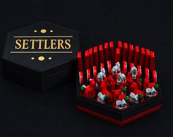 May include: A black hexagonal storage box with the word SETTLERS printed in gold on the lid. The open base contains red game pieces, including small gray buildings, gray figures, and red markers arranged in a hexagonal grid pattern.