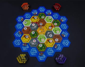 May include: A board game featuring a hexagonal grid of terrain tiles including green forests, yellow fields, brown mountains, gray hills, and blue water. Numbered circular tokens are placed on tiles, with small plastic game pieces arranged on the board.