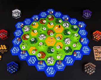 May include: A board game set featuring a large hexagonal map composed of green, yellow, and brown terrain tiles surrounded by blue water tiles. Includes colored player pieces, resource cards, and a building costs reference card.