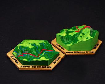 May include: Two miniature green mountain models with red and blue trail markings sit on hexagonal wooden bases. One base reads "9.14 km" and "3h 11m". The other reads "9.52 km" and "3h 57m".