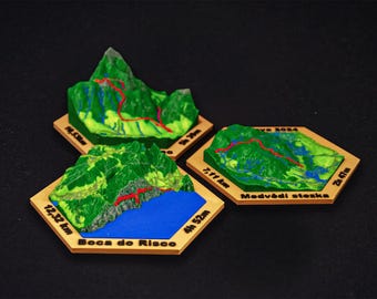 May include: Three miniature 3D topographic models of hiking trails. Each model features green terrain, a red trail, and a wooden base with text indicating distance and time. One model includes a blue body of water.