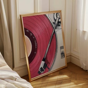 May include: A framed print of a vintage record player with a red vinyl record. The record has the words "All of a Sudden" printed on it. The frame is gold, and the artwork is leaning against a wall.