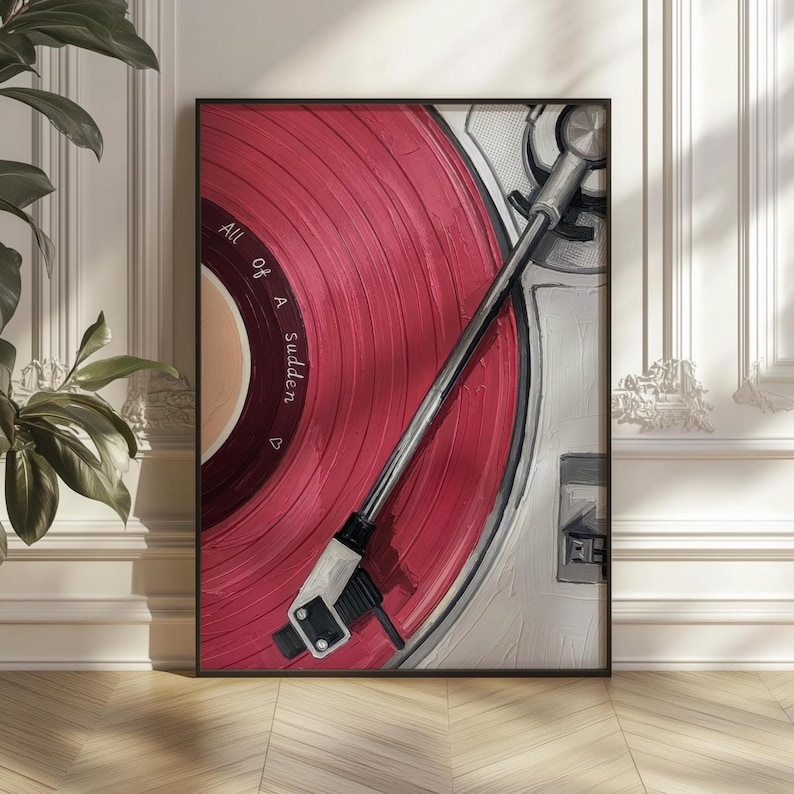 May include: A framed artwork featuring a close-up of a vintage record player with a red vinyl record. The text "All of a Sudden" is visible on the record. The record player is white and silver, set against a white wall and wooden floor.