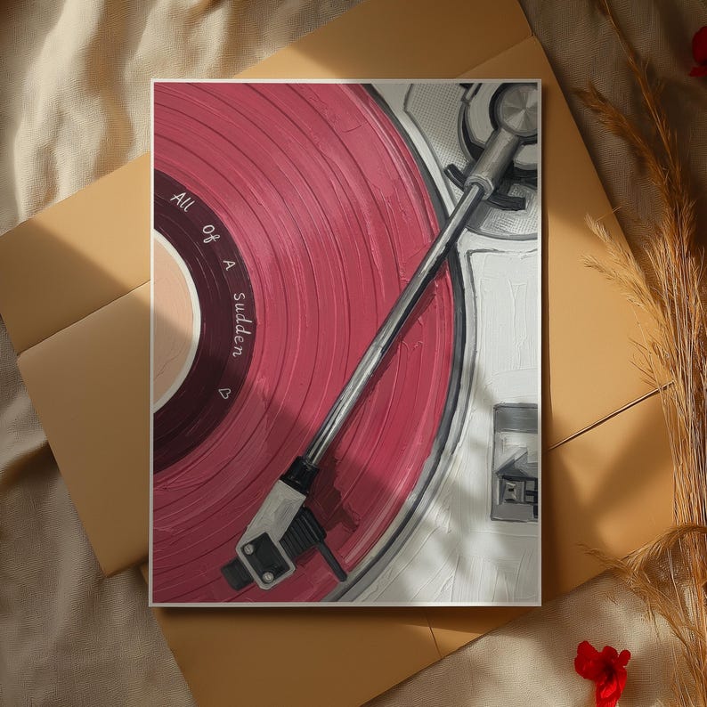 May include: A close-up of a vinyl record on a turntable. The record is a vibrant red with the words "All of a Sudden" printed on the label. The turntable arm is silver, and the background is a neutral beige.