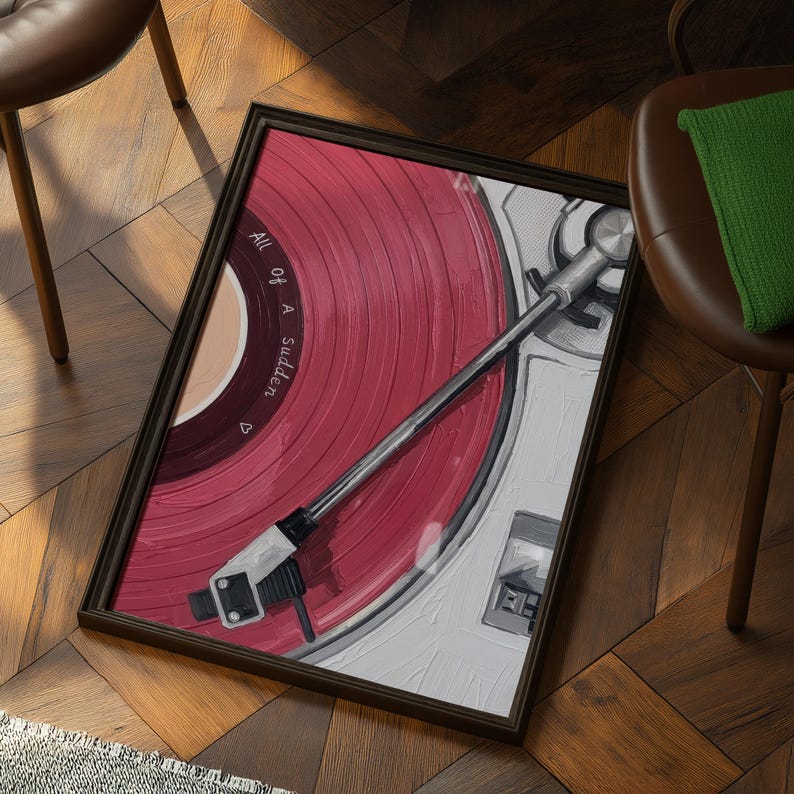 May include: Framed artwork featuring a close-up of a red vinyl record on a turntable. The record has the text "All Of A Sudden" printed on it. The turntable is white and silver, set in a dark brown frame.