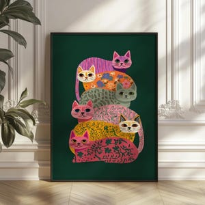 May include: A framed art print featuring a stack of five stylized cats in various colors and patterns. The cats are arranged vertically against a dark green background. The cats have pink, orange, yellow, and gray patterns.