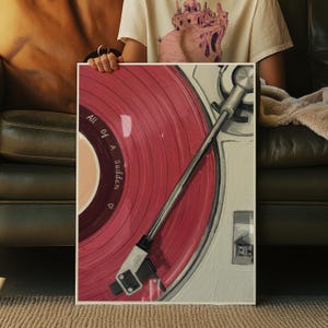 May include: A framed artwork featuring a close-up of a vintage record player with a red vinyl record. The record has the words "All of a Sudden" printed on it. The record player is white and silver.