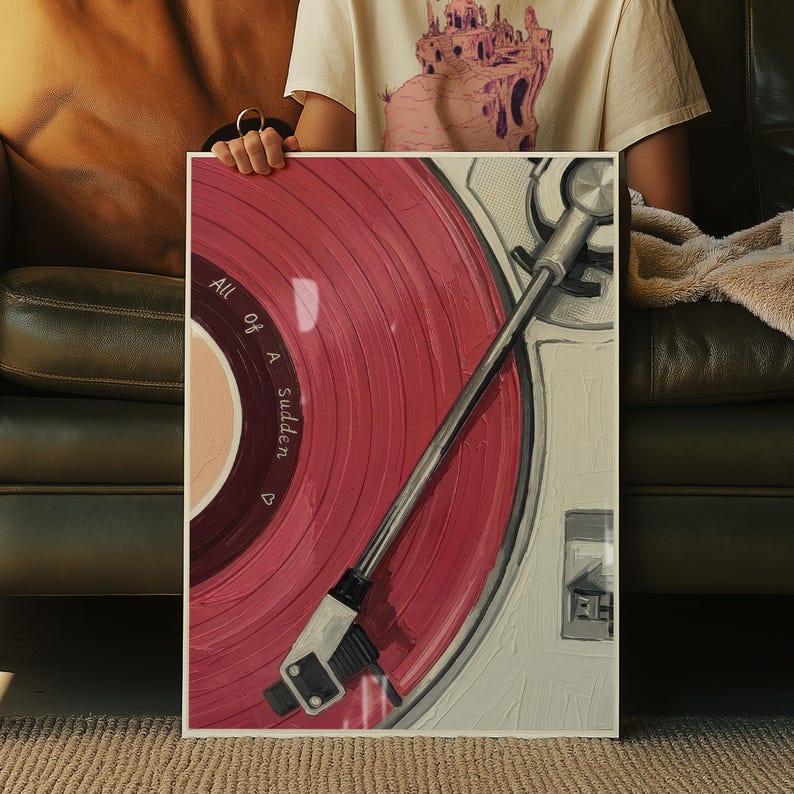 May include: A framed artwork featuring a close-up of a vintage record player with a red vinyl record. The record has the words "All of a Sudden" printed on it. The record player is white and silver.