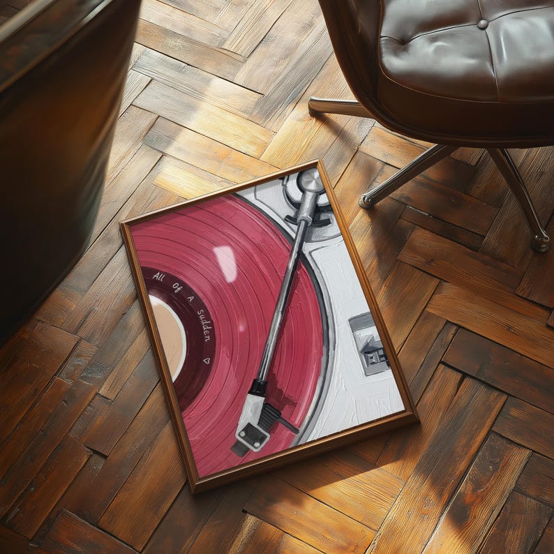 May include: A framed artwork depicting a vintage record player with a red vinyl record. The artwork features the text "All of a Sudden" and is set against a white background. The frame is a warm brown color.