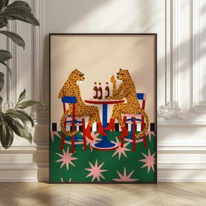 May include: A framed art print depicting two cheetahs at a table with bottles and cigarettes. The cheetahs wear red boots and sit on blue and red chairs. The table is blue and red, and the background is a green carpet with pink and white star shapes.