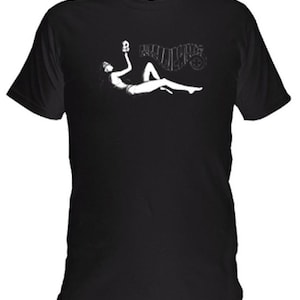 May include: Black t-shirt featuring a white graphic of a reclining figure holding a skull, with the word "PALLBEARERS" above. The design is a stylized illustration. The shirt has short sleeves and a crew neck.