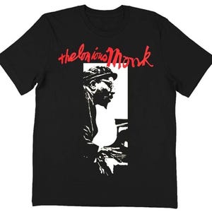 Könnte beinhalten: Schwarzes T-Shirt mit rotem Schriftzug "Thelonious Monk". Auf der Vorderseite des Shirts befindet sich ein Schwarz-Weiß-Bild von Thelonious Monk beim Klavierspielen. Ein klassisches Design.