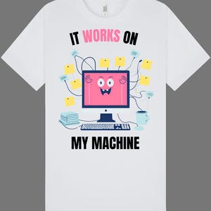 May include: White t-shirt featuring a black and white illustration of a computer with a smiley face. The text "IT WORKS ON MY MACHINE" is printed on the shirt.