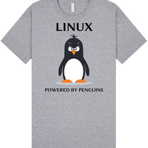 Può includere: Una maglietta grigia con la scritta "LINUX" in nero sopra un pinguino dei cartoni animati con un'espressione arrabbiata. Il testo "POWERED BY PENGUINS" è sotto il pinguino. Il pinguino è bianco e nero con i piedi arancioni.