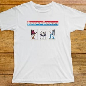 May include: White t-shirt with the text "HEAVY DREAM" in blue and red. Below the text are three small illustrations of musicians playing instruments. The illustrations are in a rectangular frame.