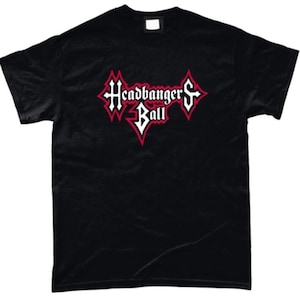 Puede incluir: Camiseta negra con la frase "Headbanger's Ball" en una fuente gótica estilizada con detalles rojos y blancos. El diseño está centrado en la parte delantera. La camiseta tiene mangas cortas y cuello redondo.